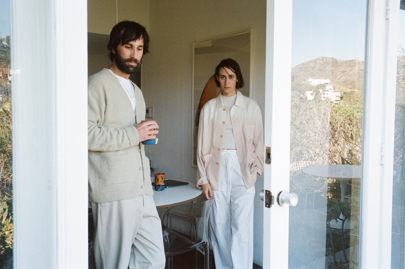 Rel wears Cotton Linen Cut Shaggy Knit Cardigan in Light Green, Hard Twist Finx Heavy Chino Slacks in Khaki, Suede Moccasin Slippers in Beige. Clara wears White Cashmere Herringbone Coverall in Beige Dye, Dry Cotton Knit Vest in Ivory, Washed Finx Twill Easy Wide Pants in White