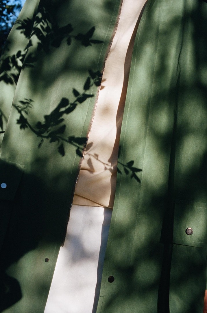 Rel wears Silk Polyester Grosgrain Soutien Collar in Green, Super Soft Jersey Mock-Neck Tee in Ivory, Hard Twist Finx Heavy Chino Slacks in White