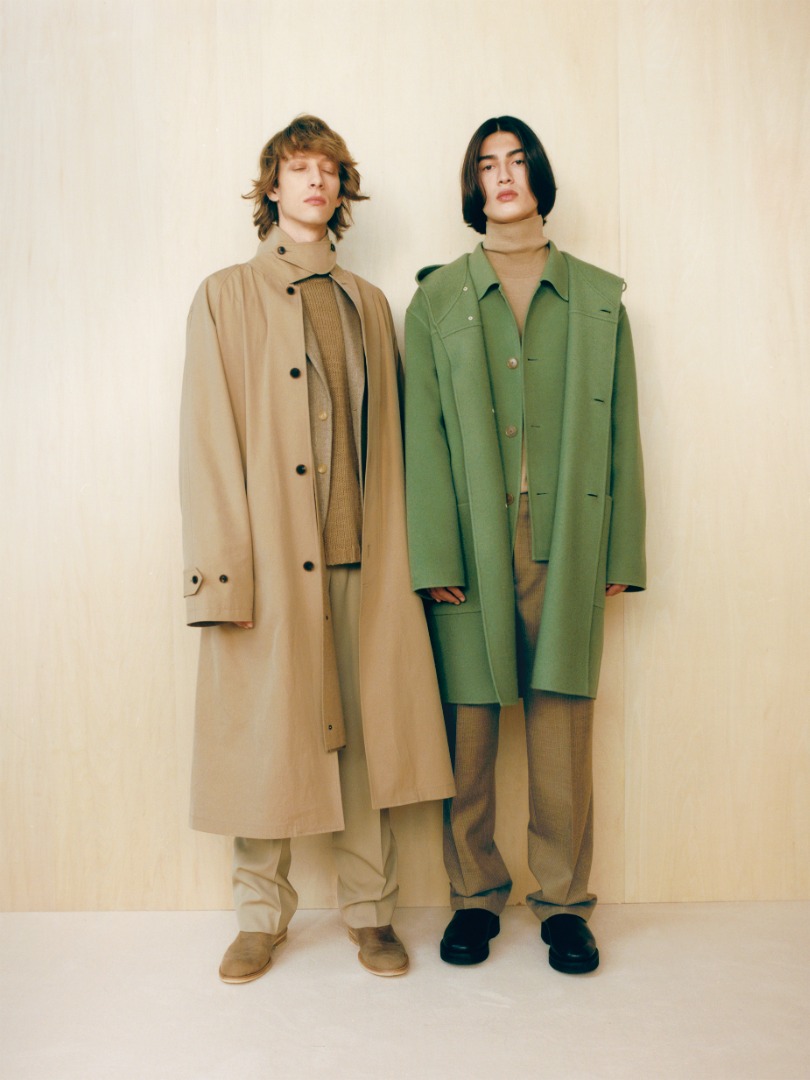 Kaan wears Velour Brushed Wool Melton Hand Sewn Hooded Coat in Sage Green. Josef wears Finx Hard Twist Gabardine Soutien Collar Coat in Beige Chambray